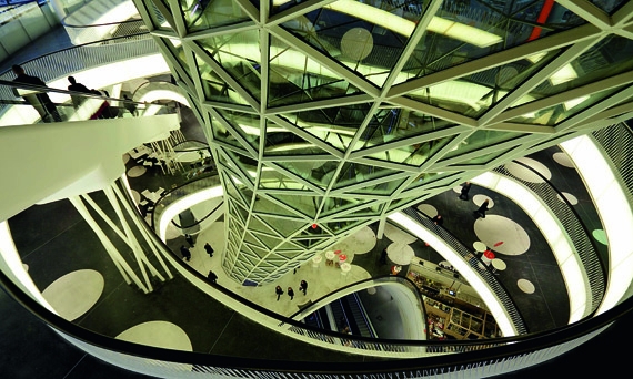 Особенность этого необычного сооружения – два полых «водоворота», как называет их сам архитектор Массимилиано Фуксас. Первый соединяет все ярусы постройки, как бы втягивая оболочку здания внутрь с крыши. Второй «водоворот» совмещает главный фасад и крышу ТЦ «Майцайль» – сквозь него видно небо. Особенность этого необычного сооружения – два полых «водоворота», как называет их сам архитектор Массимилиано Фуксас. Первый соединяет все ярусы постройки, как бы втягивая оболочку здания внутрь с крыши. Второй «водоворот» совмещает главный фасад и крышу ТЦ «Майцайль» – сквозь него видно небо.